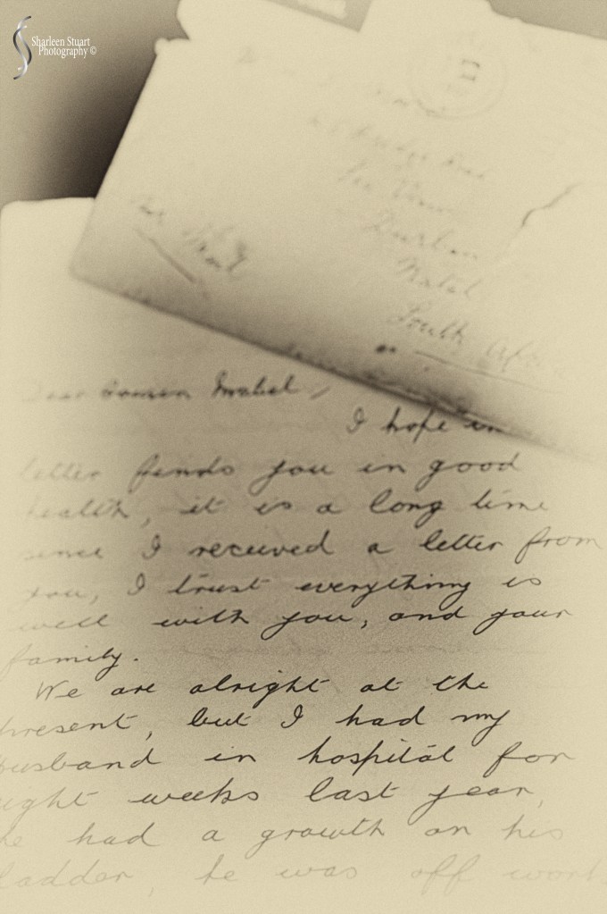 A close-up view of old handwritten letters on a wooden surface, showcasing cursive writing and vintage paper details.